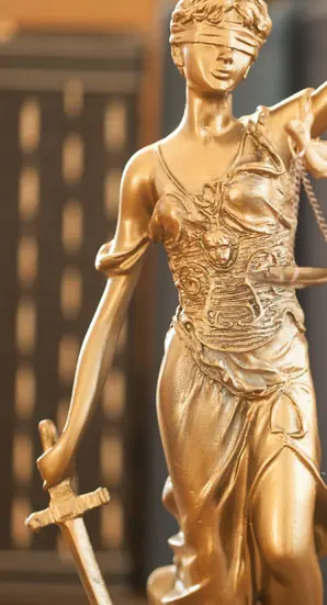 Justitia-Statue mit Schwert und Waage, symbolisiert Recht und Gerechtigkeit in seriöser Atmosphäre.